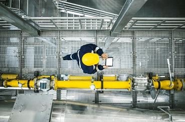 Mann mit Bauhelm auf Anlagenbrücke